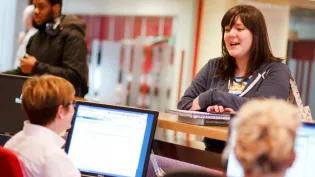 Students speak to staff over a counter.